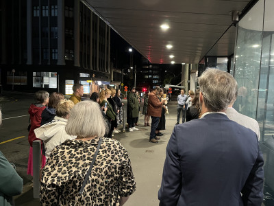 A group of people gather outside an office building at dawn.