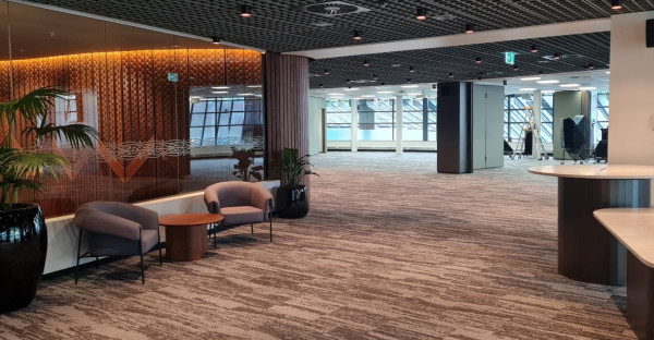 An open office space with large windows featuring plants, tables and seating.