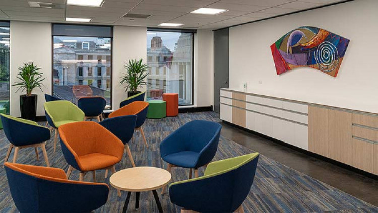 An example of a sitting area with coloured chairs, bright artwork and small tables.