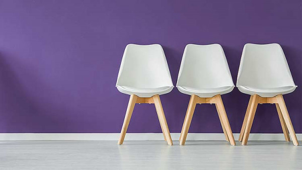 An example of high visual contrast, showing a white chair against a purple wall with a grey floor.